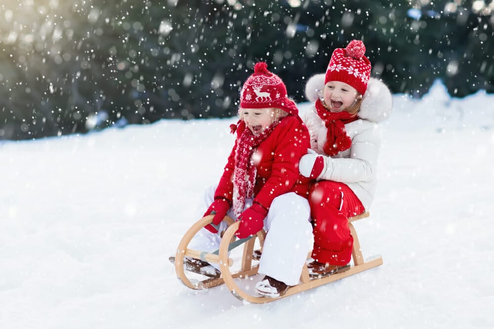Children going down a snowy hill on a sled